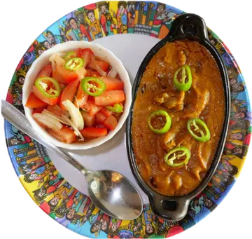 Bozena Shiro in an oval dish beside salad and injera.