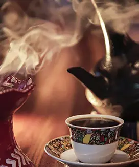 Coffee poured from a jebena pot into a small cup.