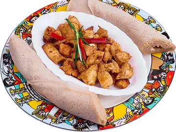 Doro Tibs chicken pieces on an injera-lined plate.