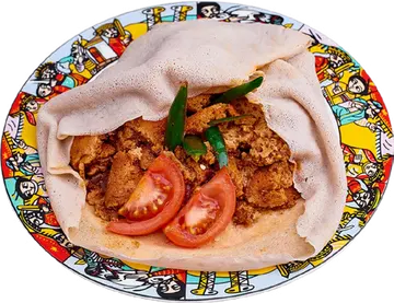 Firfir on injera with sliced tomato and a pepper.