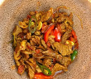 Merek Tibs with pieces of red and green pepper.