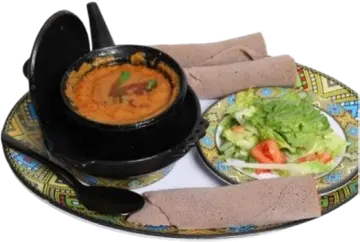Shiro in a black pot beside salad and injera.
