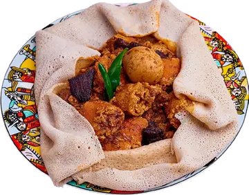 Siga Firfir with pieces of injera and a green pepper.