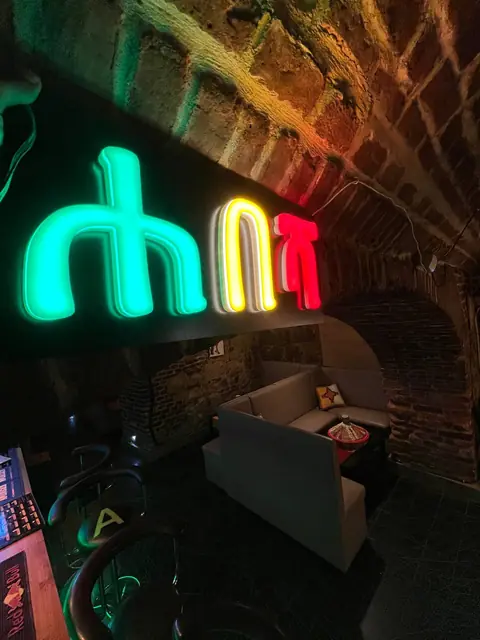 The bar, where a neon sign spells the restaurant's name in Amharic in the colours of the Ethiopian flag.